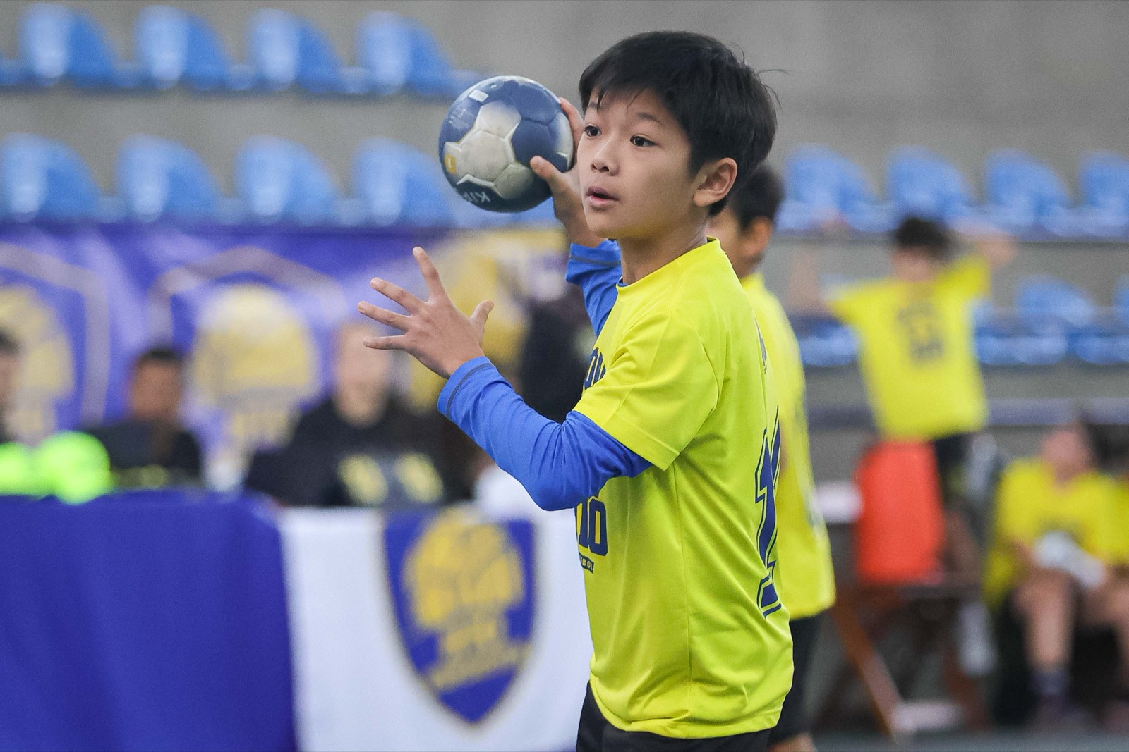 Menino da H10 concentrado recebendo a bola de handebol durante o jogo